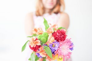 Eine Frau mit einem Blumengruß lächelt in die Kamera