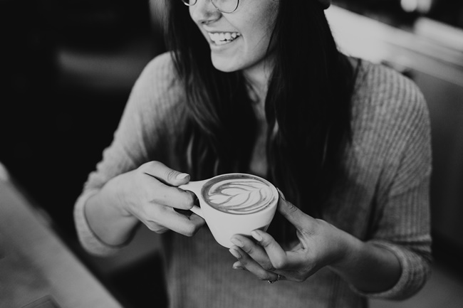 Eine Frau trinkt Kaffee und ist durch gute Gedanken glücklicher