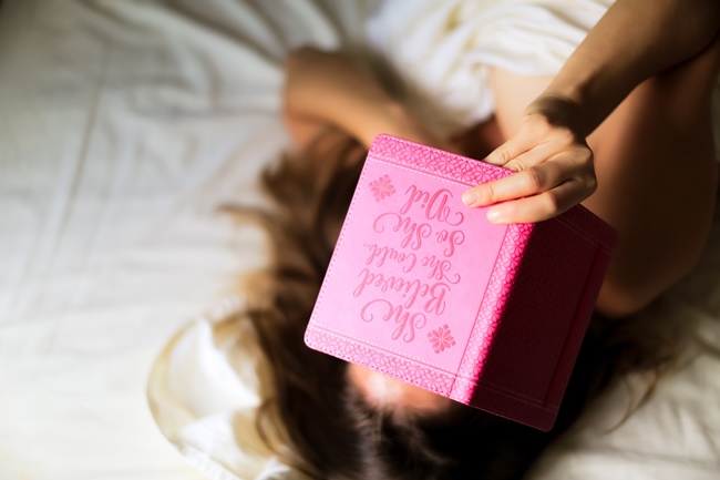 Eine Frau liegt im Bett mit Journaling book
