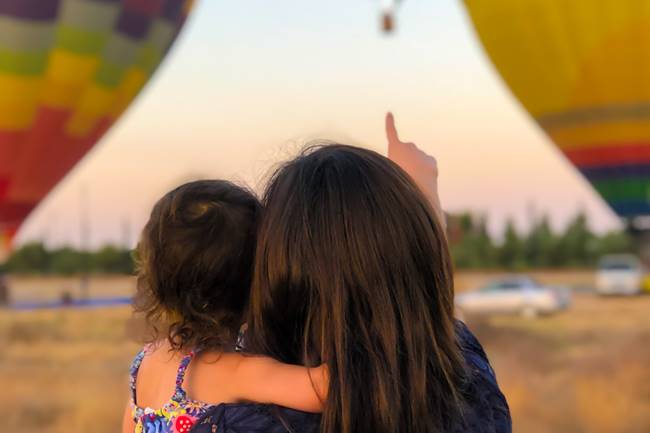 Mutter zeigt Kind Heißluftballons