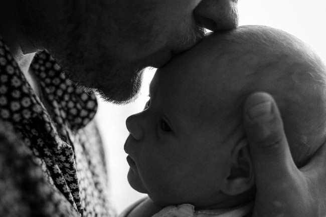 Mann küsst ein Baby - Nähe brauchen wir von Beginn an