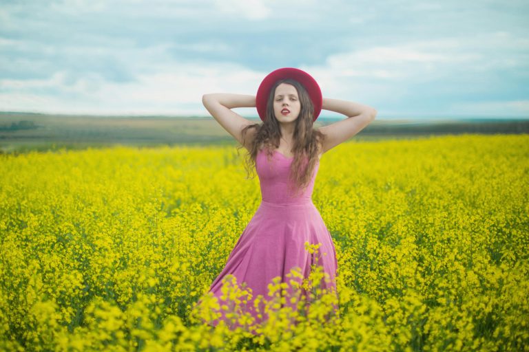 Frau mit Hut steht selbstsicher in der Blumenwiesen, sie ist ein Rebell