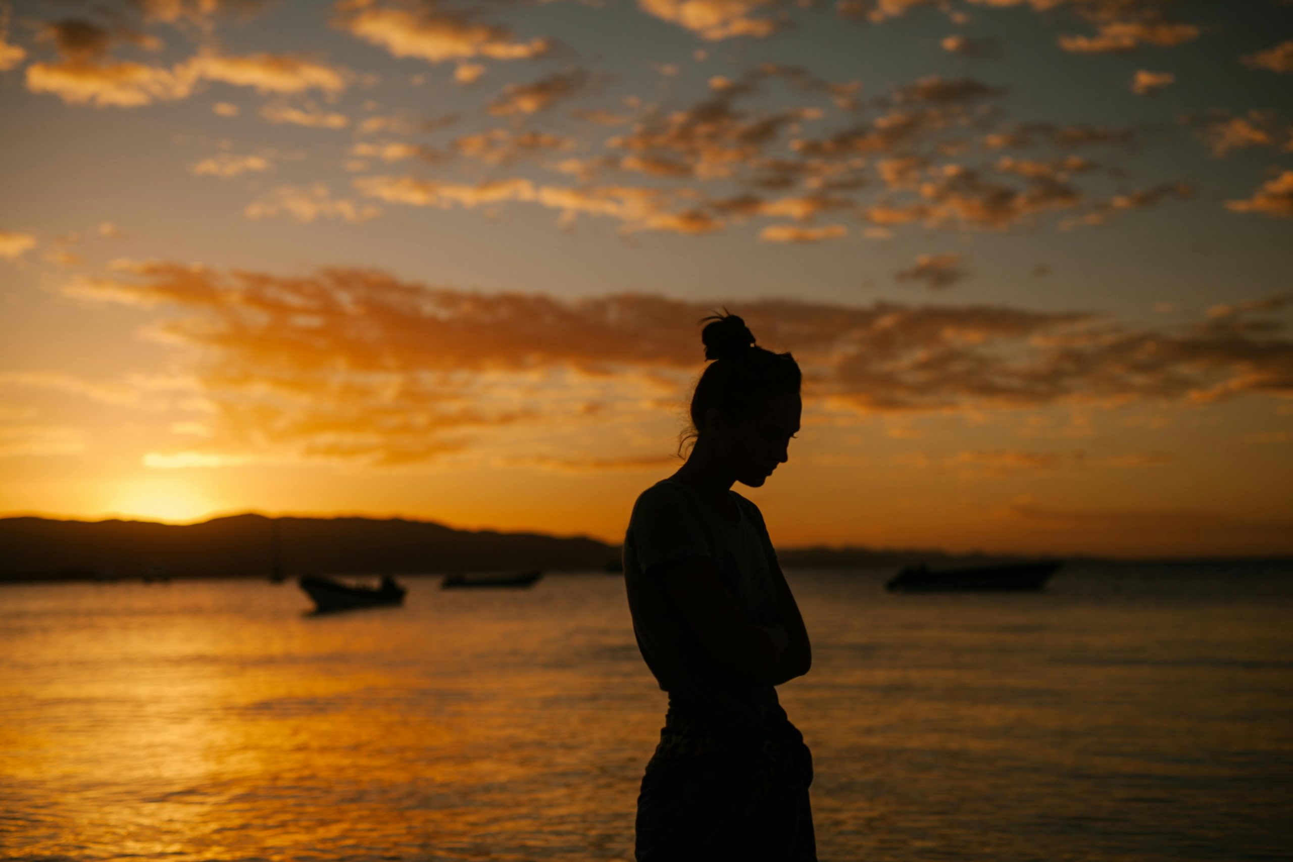 Frau bei Sonnenuntergang am schönen Strand, geplagt von schlechtem Gewissen